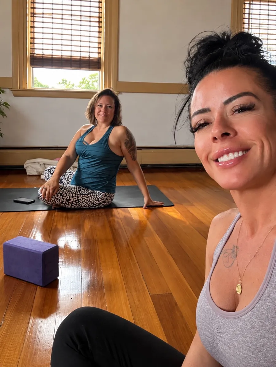Two smiling students on their mats in the sunlit practice room